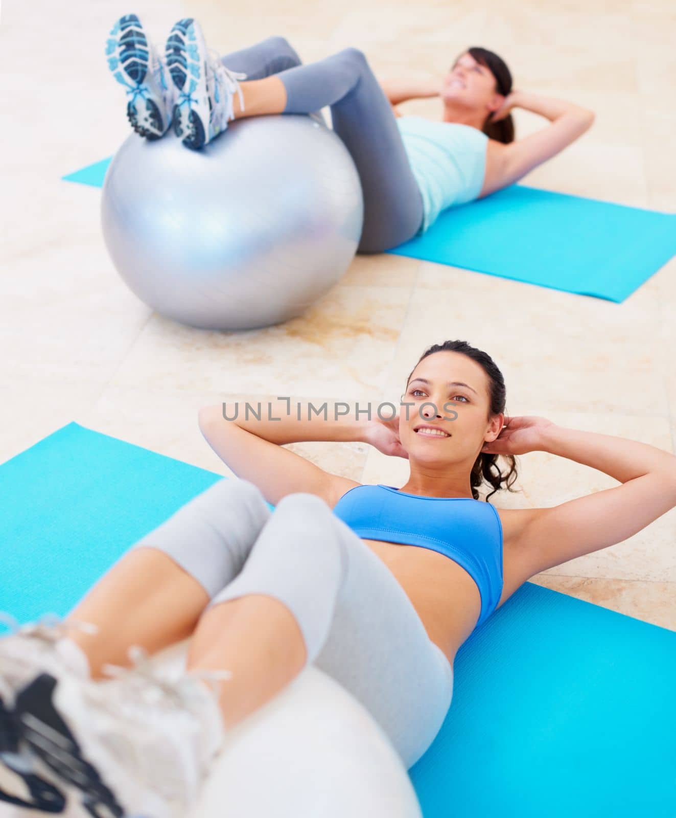 Committed to flawless abs. Fit woman doing a sit up during a pilates class. by YuriArcurs