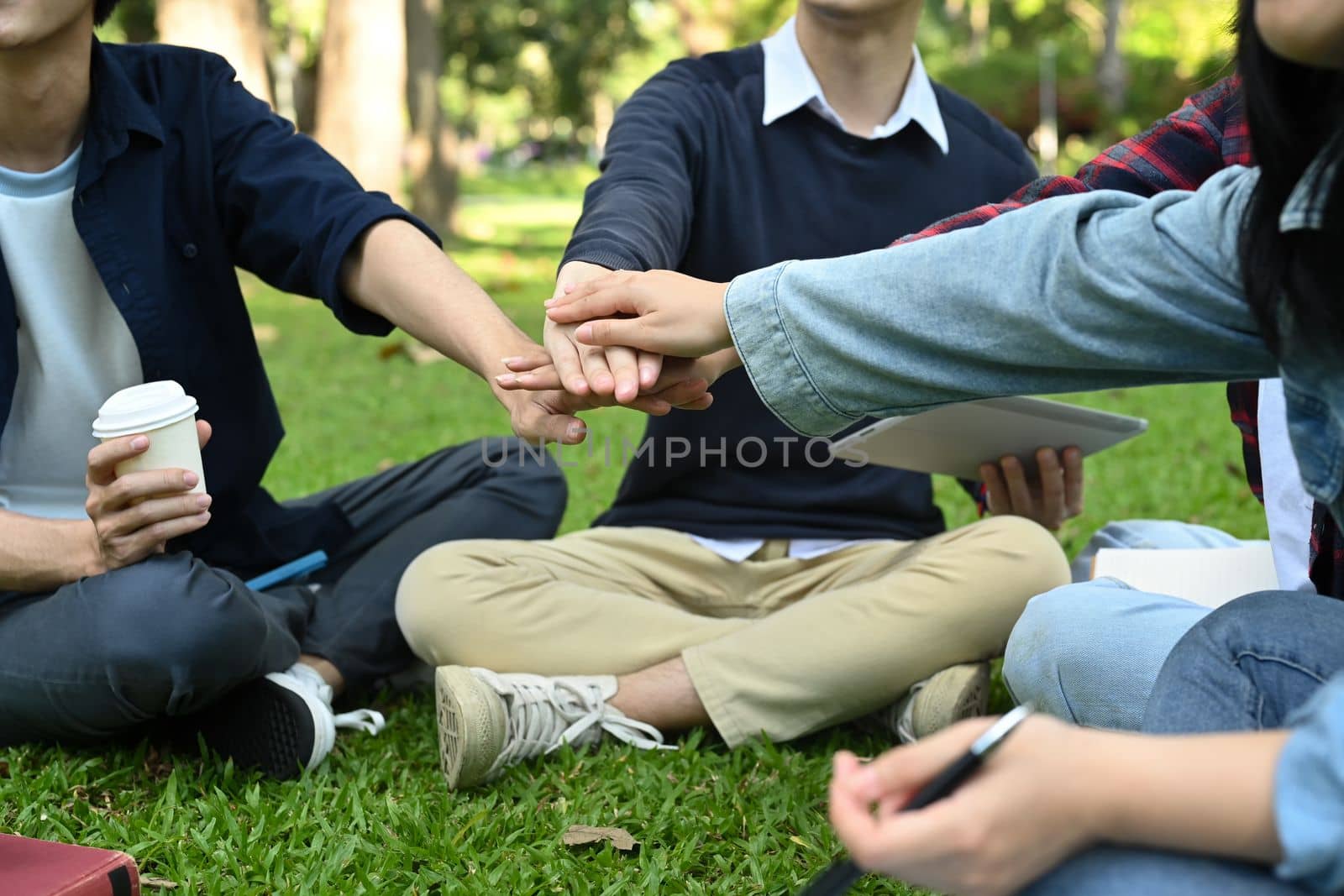 Cropped shot of university students are stacking hands, celebrating together. University, youth lifestyle and friendship concept.