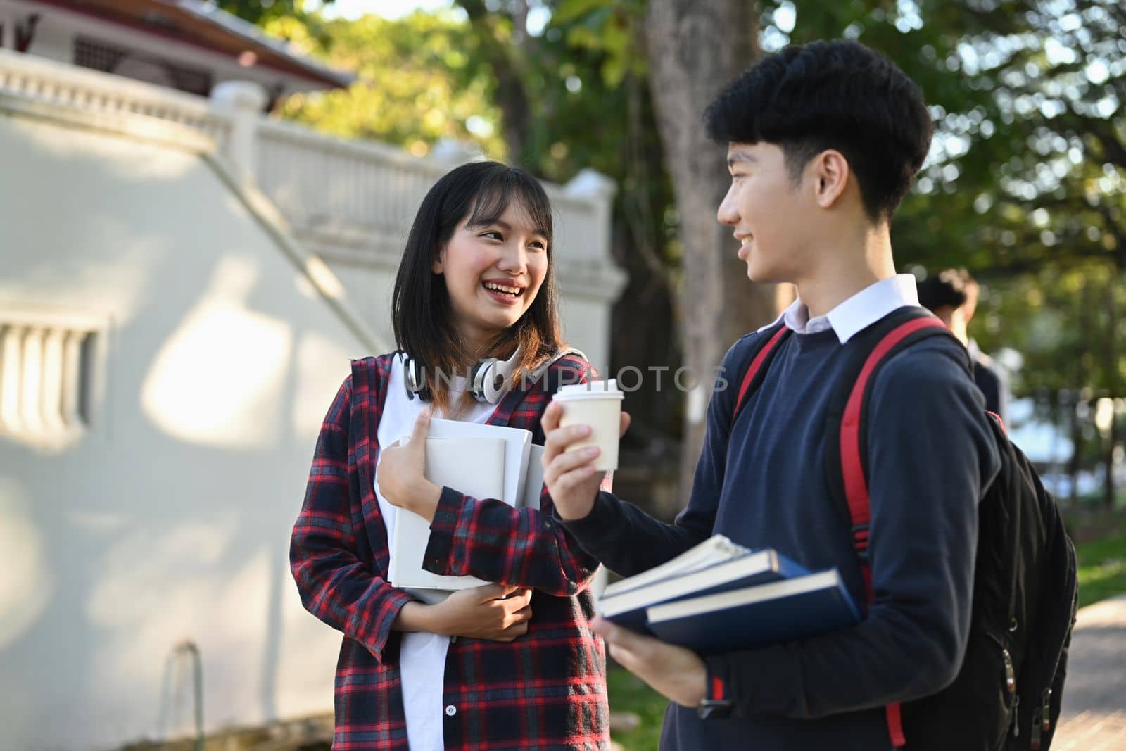 Two smiling college student walking after to college building and discussing the project or sharing the ideas.