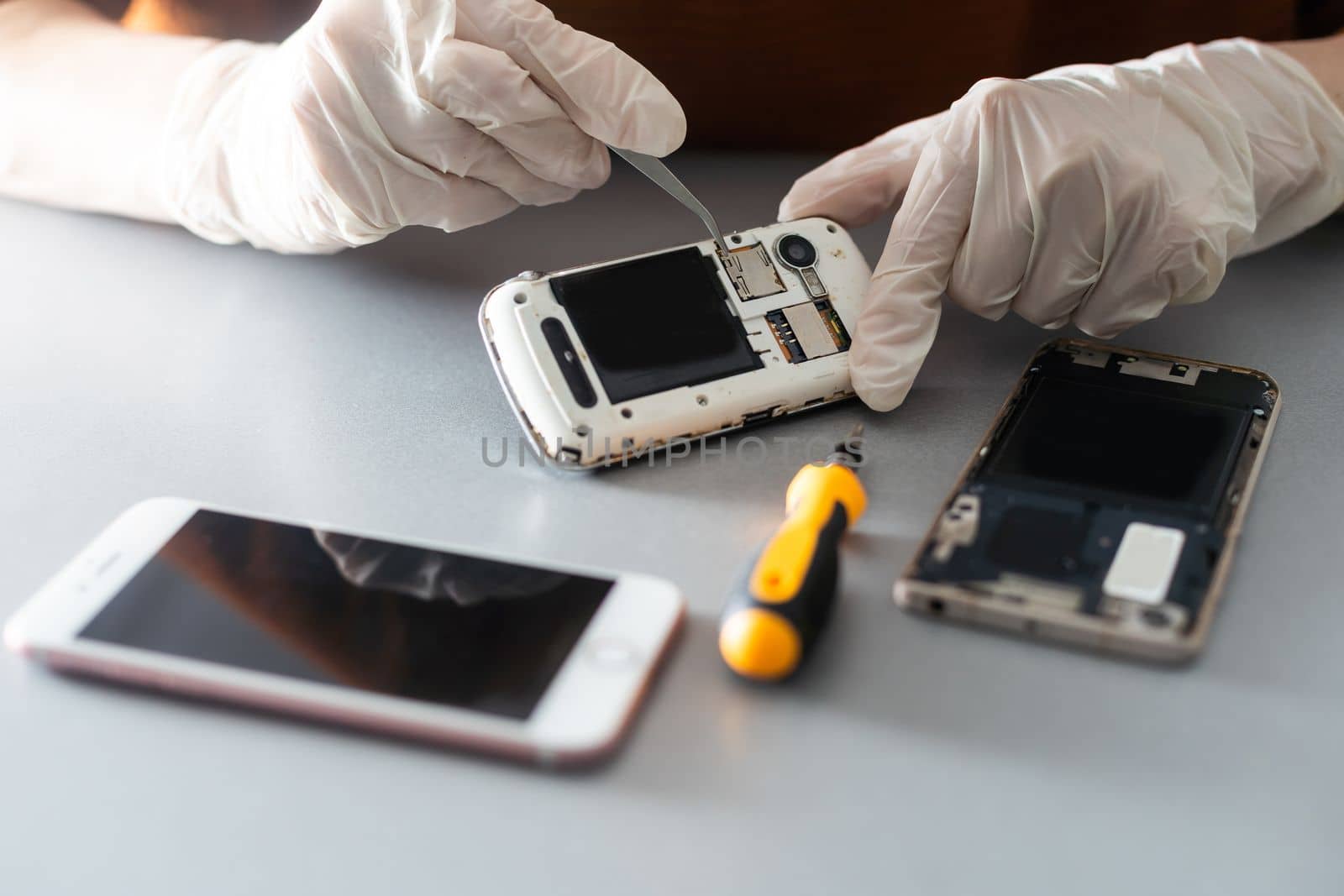 Technician repairing inside of mobile phone by soldering iron. the concept of data, hardware, technology