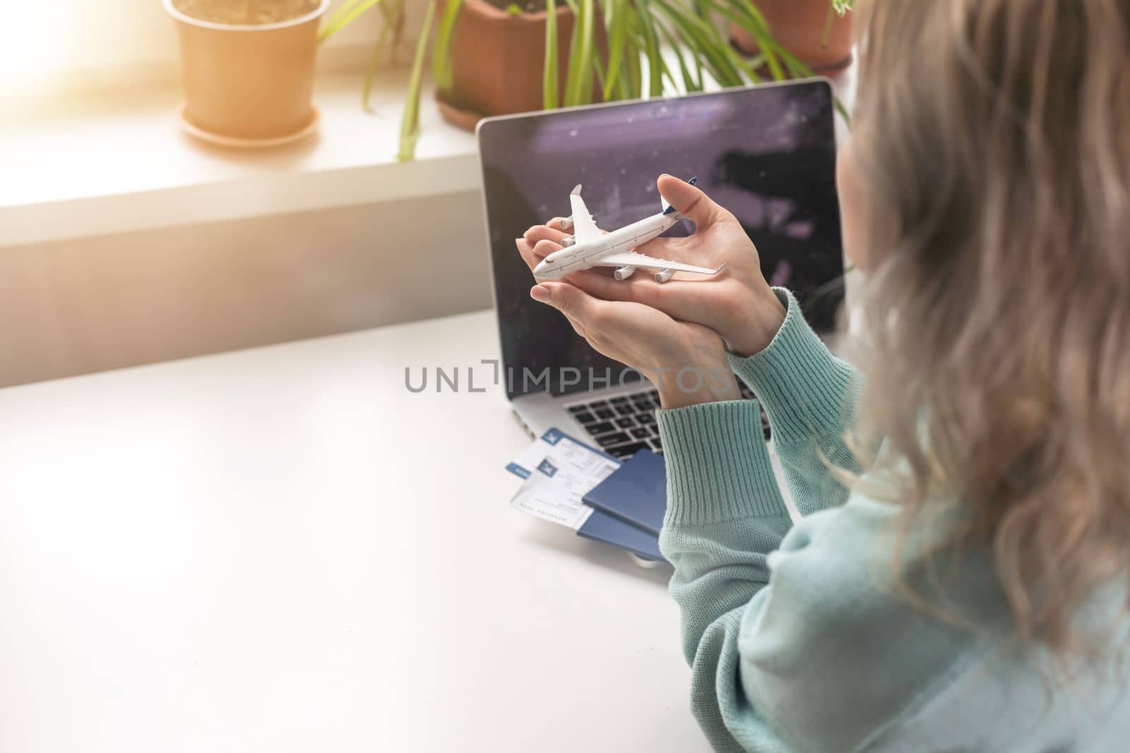 Woman dreaming about travel while self isolation at home. Caucasian girl with toy airplane and laptop.