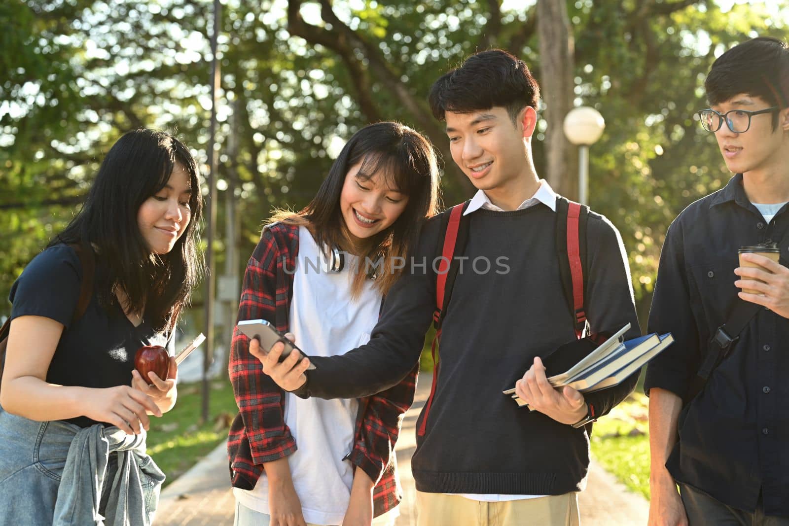 Diverse young college friends talking to etch other while walking after classes in university campus outdoors.