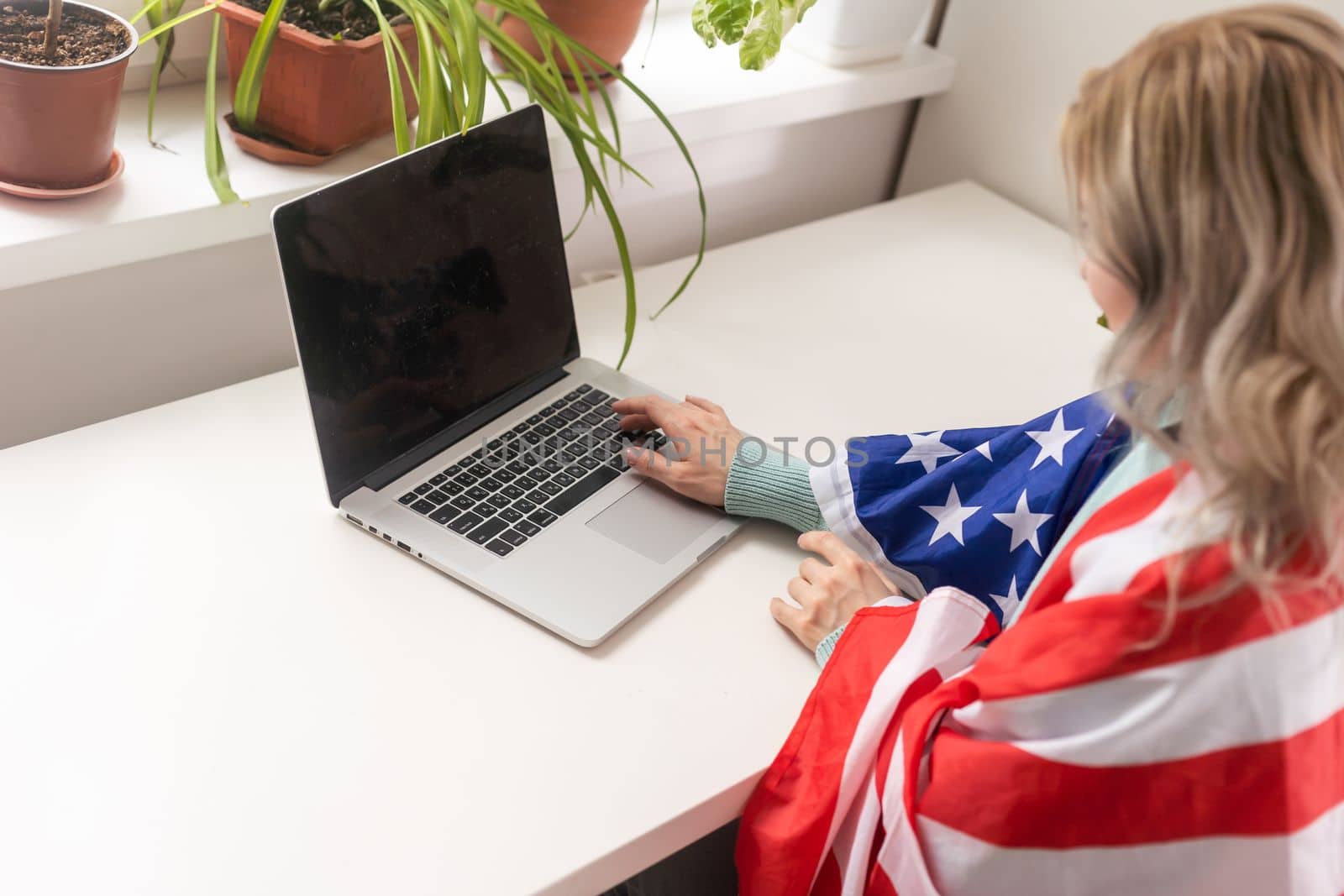 Positive teacher in headset having online lesson on laptop near flags in school.