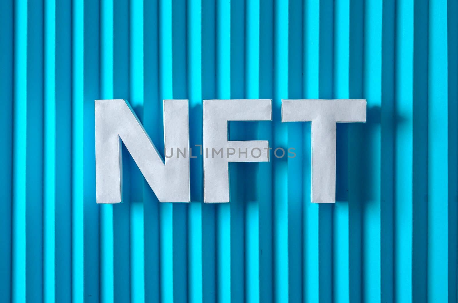 NFT text letters on a blue background. Minimal is the concept of digital modern technologies of crypto tokens and sales of the future. by sergii_gnatiuk