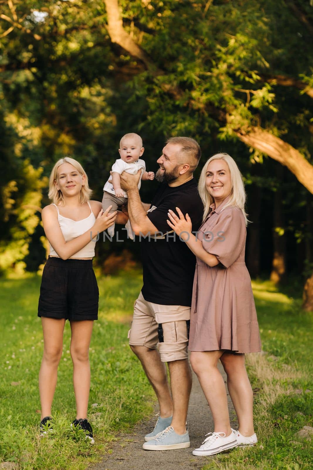 Happy family in the park of four people in the summer in the park in nature by Lobachad