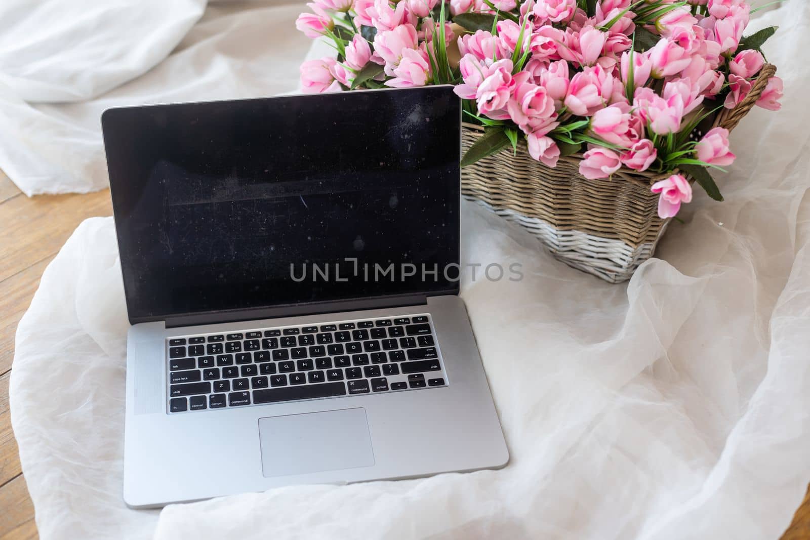 Table with laptop and flowers in a basket.