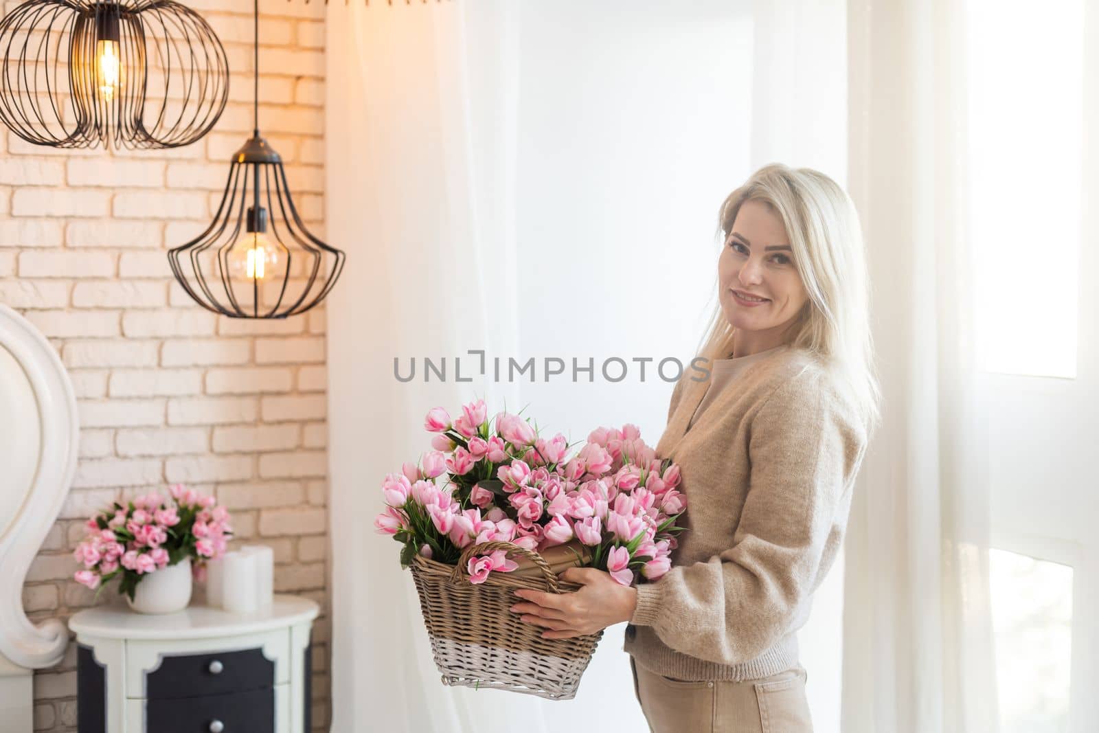 woman decorates her house with flowers. woman collects a bouquet at home in the kitchen. spring mood. by Andelov13