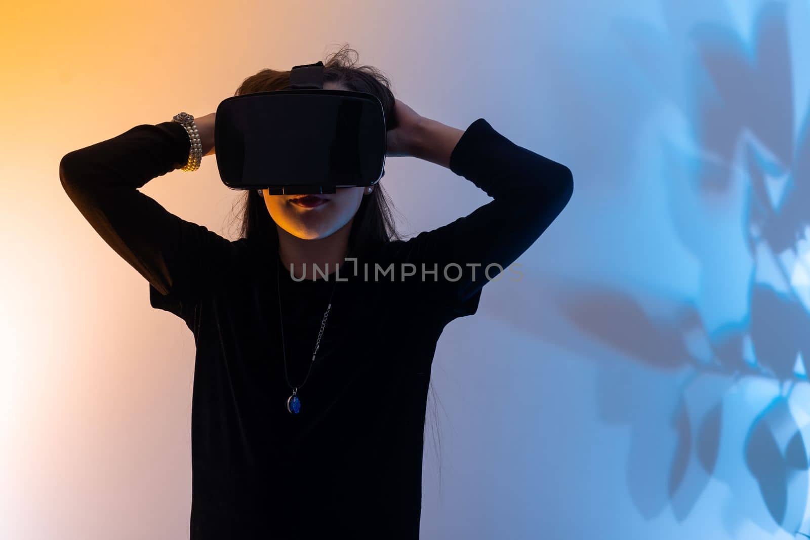 Teenage girls are having fun playing VR glasses virtual reality metaverse playing games, watching movies, listening to music, shopping. Colorful neon futuristic backgrounds, digital future technology