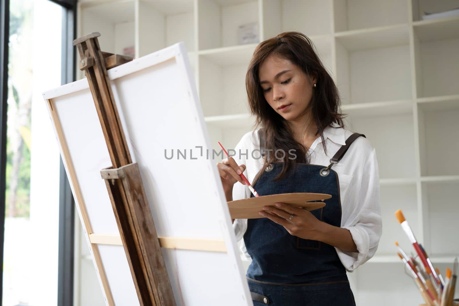 Artist woman painting with watercolors in the workshop.