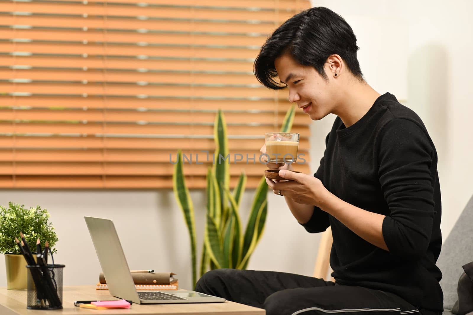 Man drinking coffee and reading news on laptop computer at the morning. by prathanchorruangsak