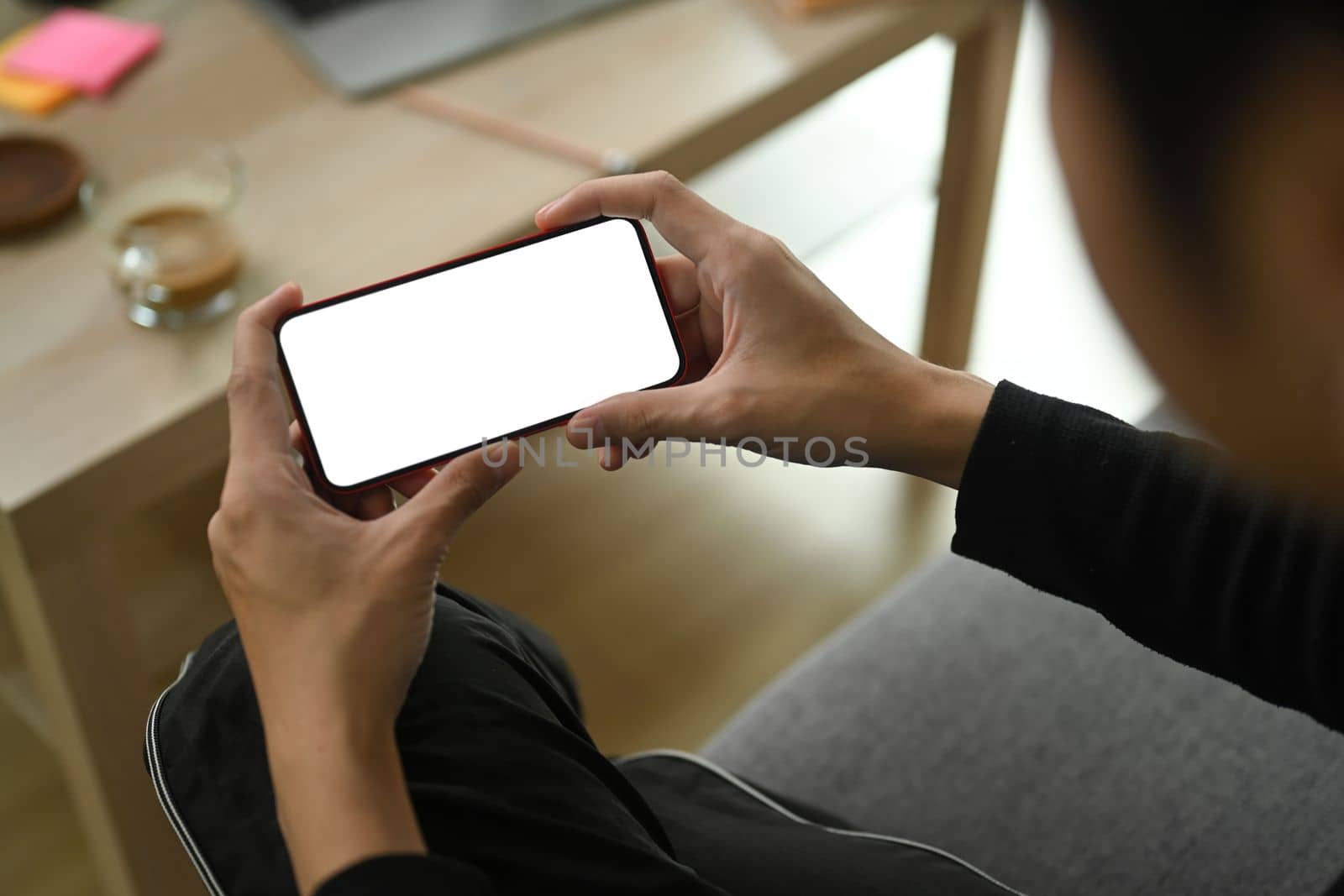 Close up view man sitting on sofa and using smart phone.