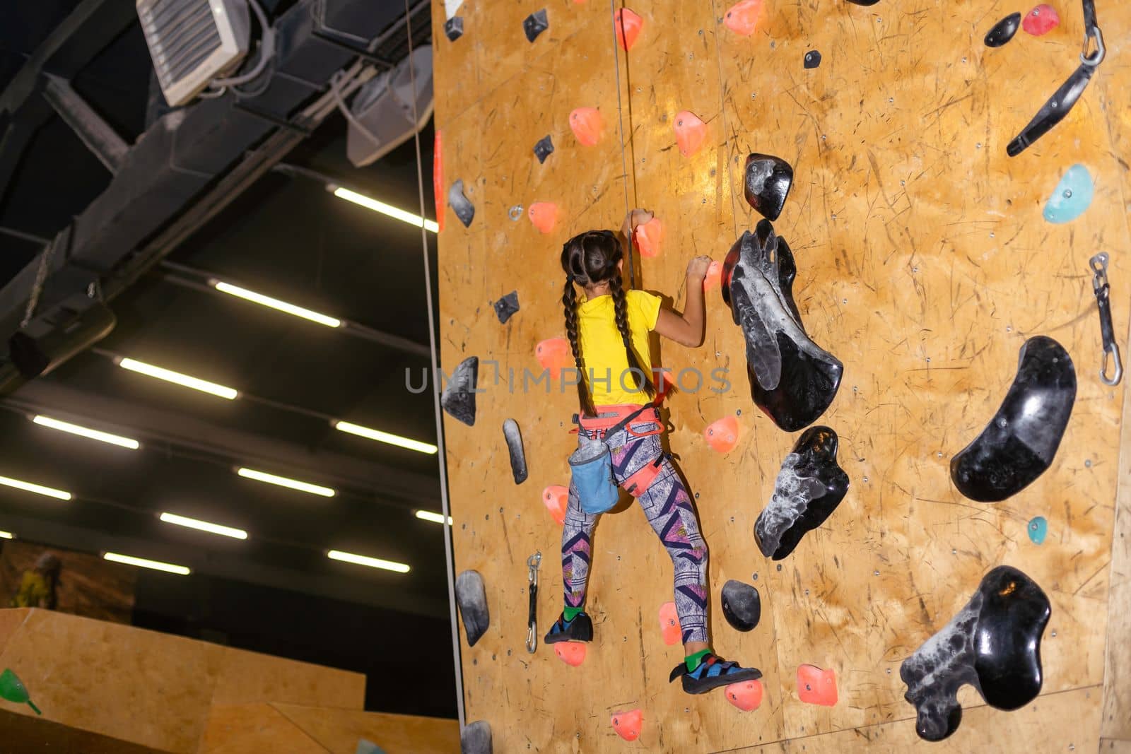 bouldering, little girl climbing up the wall.