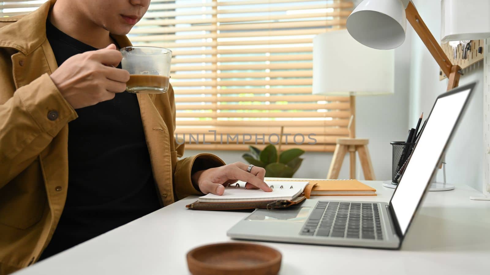 Young man drinking hot coffee and using laptop computer. by prathanchorruangsak