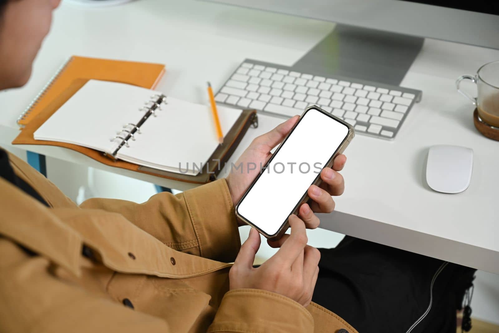 Cropped shot man using smart phone while sitting at his workplace.