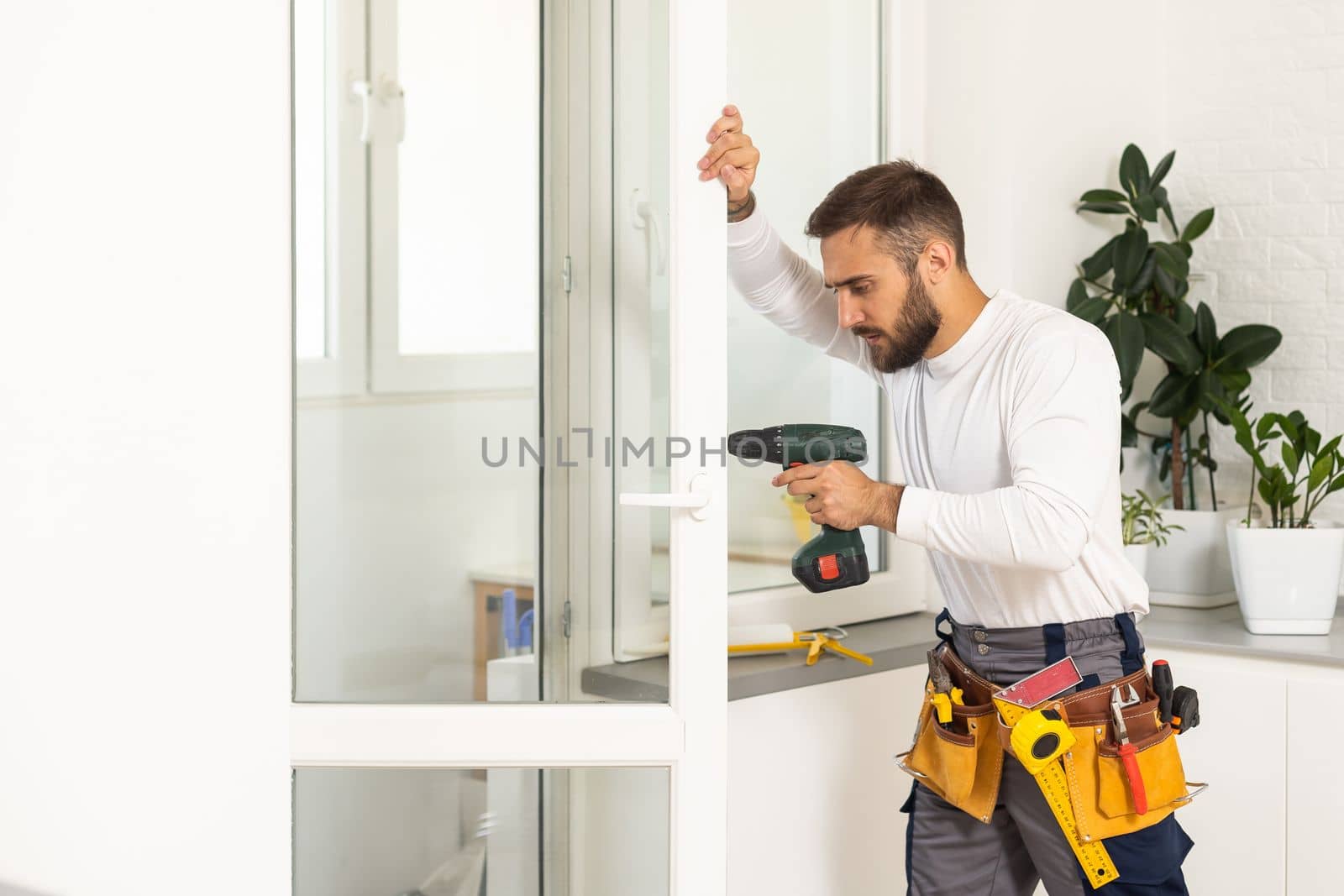 handsome young man installing bay window in a new house construction site