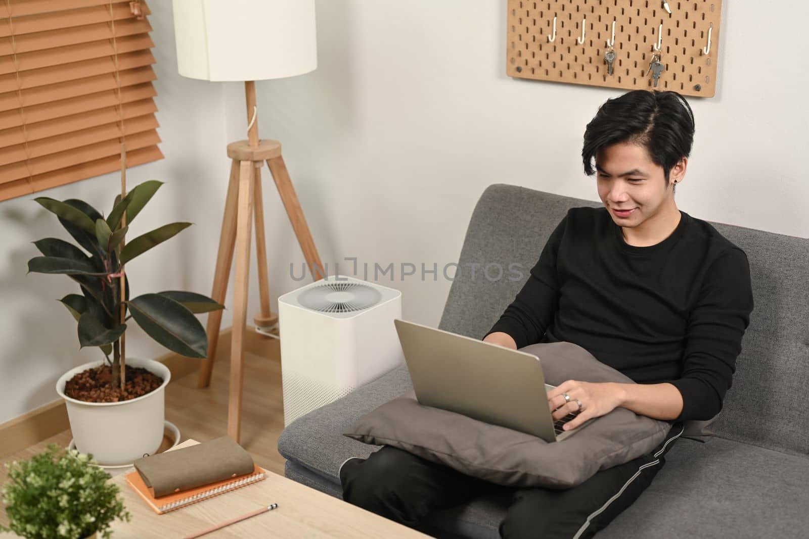 Young man surfing internet with laptop on sofa. by prathanchorruangsak