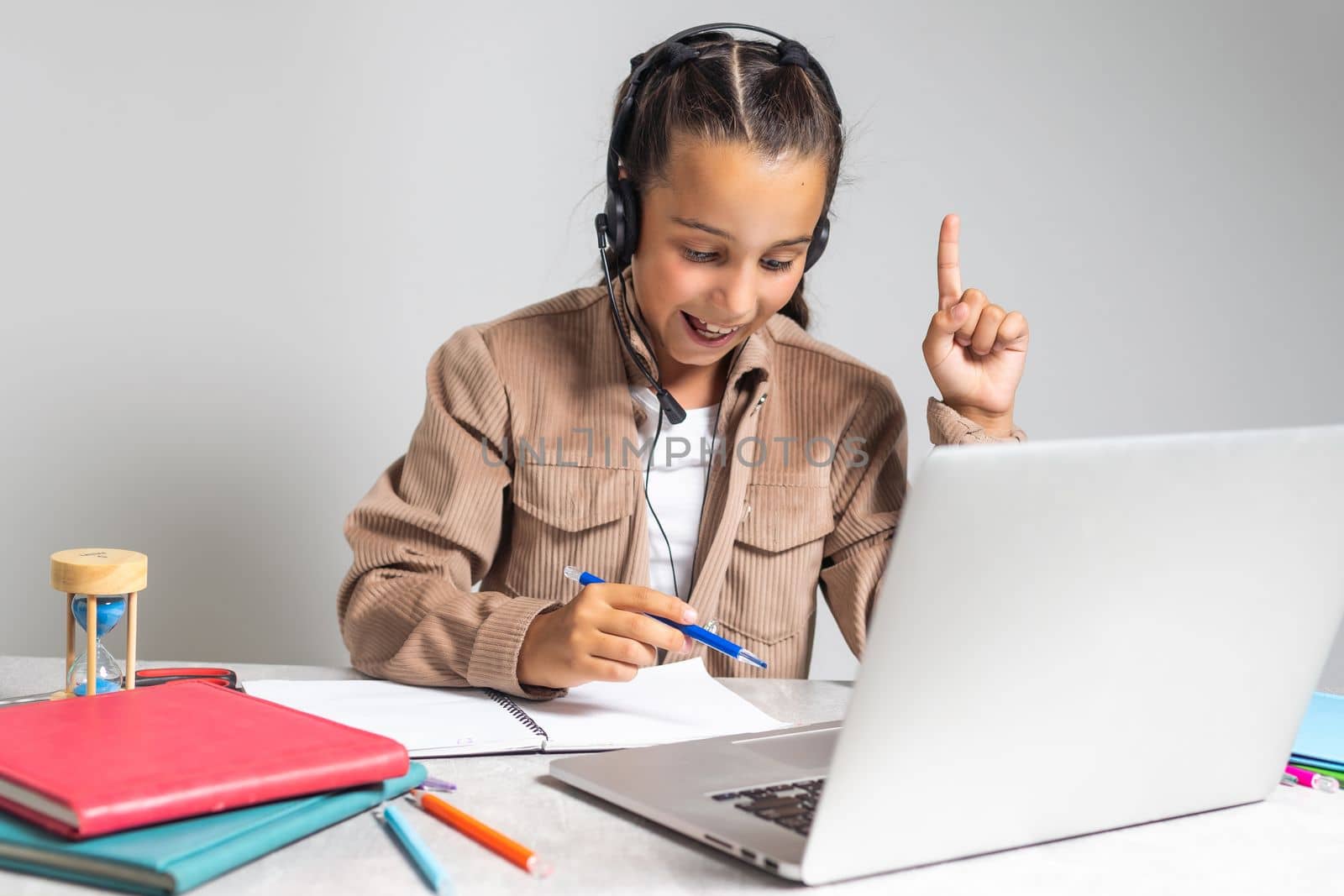 caucasian girl sitting at the desk and writing in a notebook and doing homework