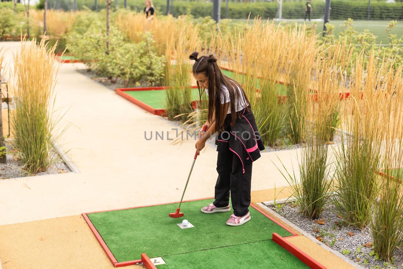 Cute little girl playing mini golf in a park