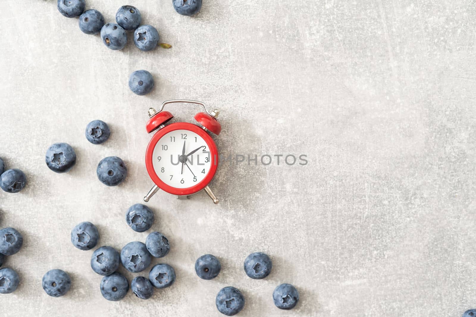 vintage alarm clock on blueberry background. by Andelov13