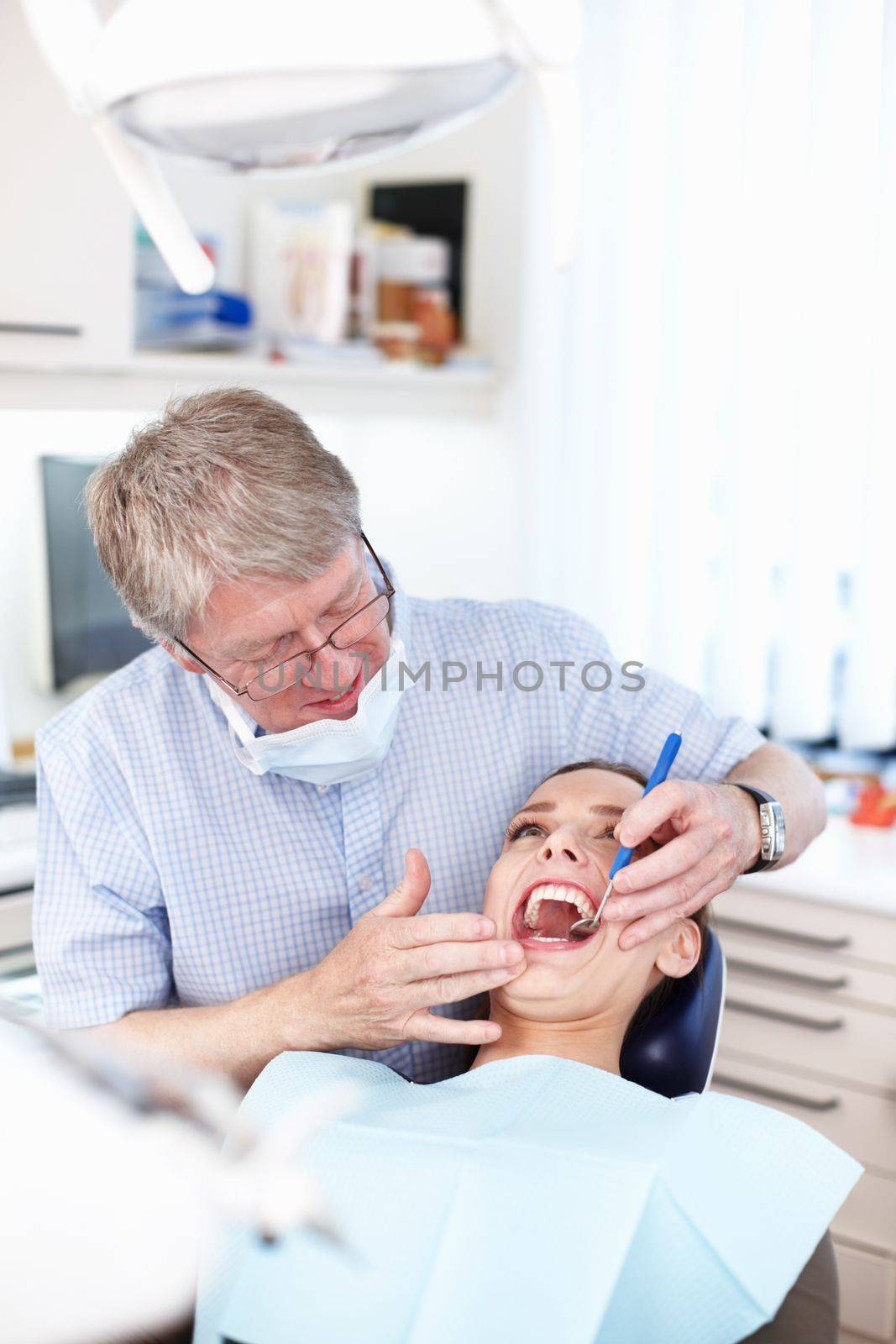 Check up visit. Portrait of male dentist checking patients teeth. by YuriArcurs