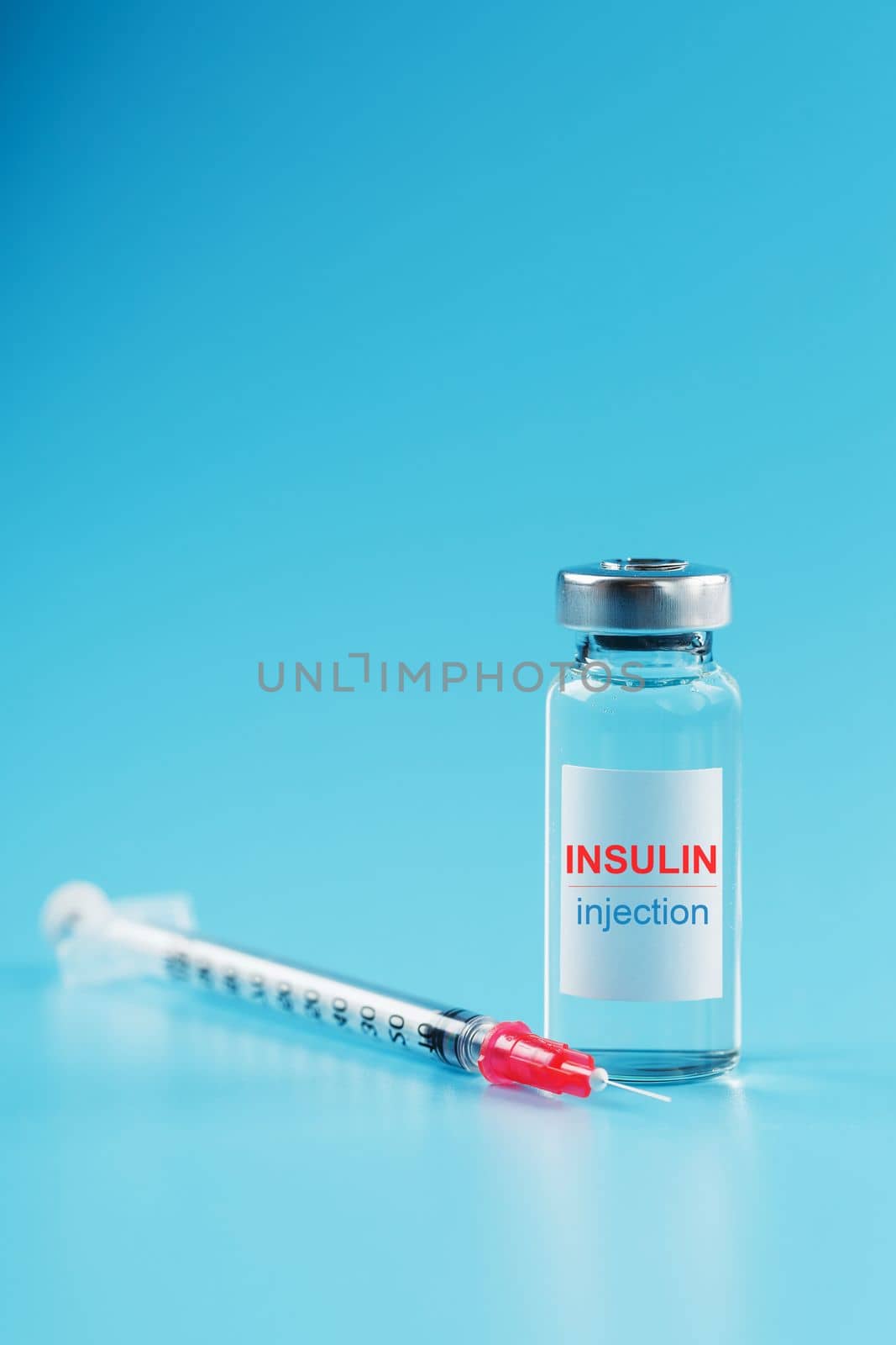 A bottle of insulin hormone and a syringe on the table on a blue background