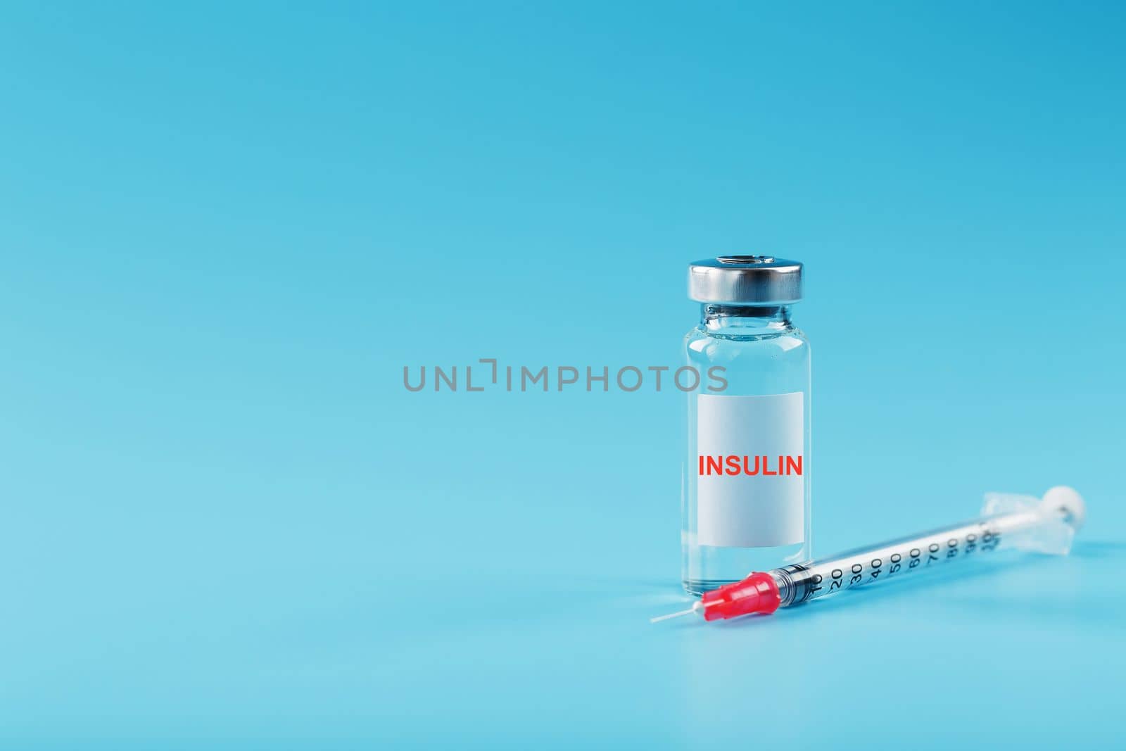 A bottle of insulin hormone and a syringe on the table on a blue background