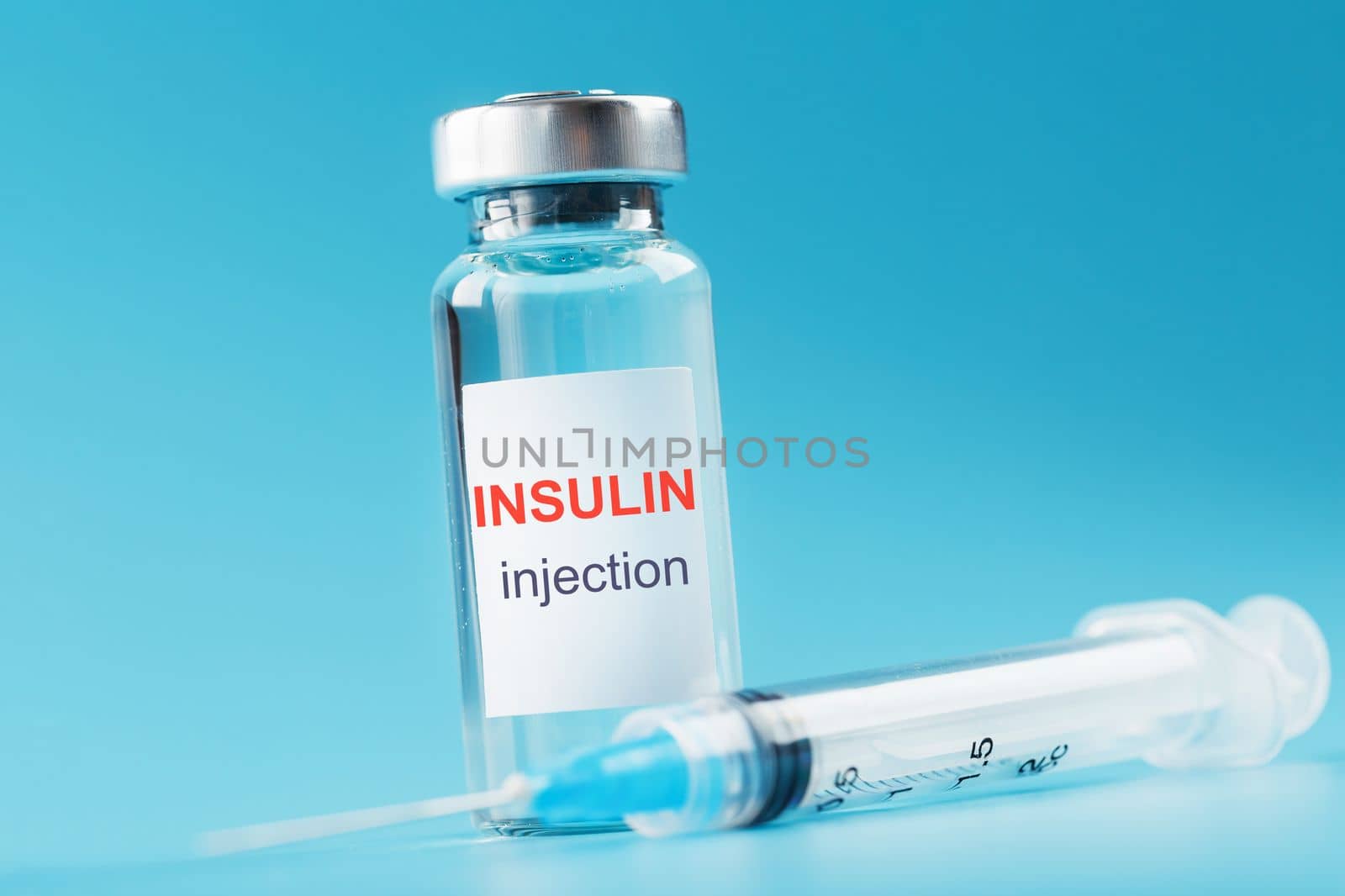 A bottle of insulin hormone and a syringe on the table on a blue background