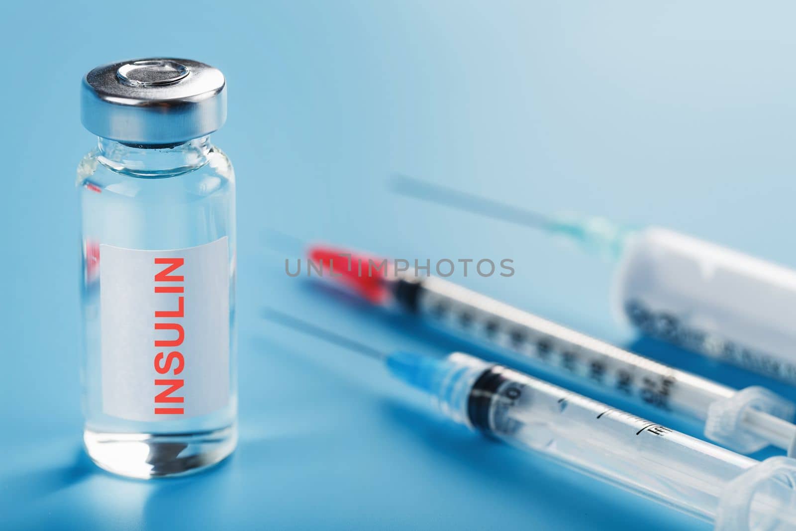 Ampoule bottle with insulin, needles and syringes for medical subcutaneous injection on a blue background