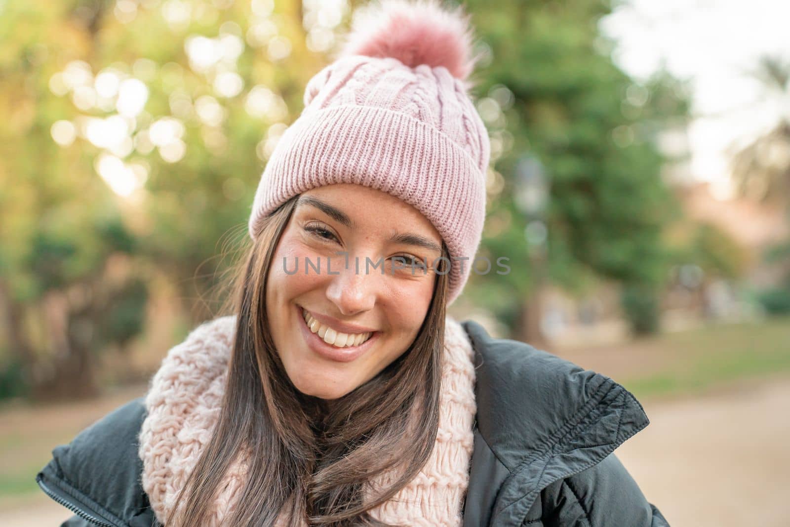 Young joyful woman smiling at camera outdoors on a sunny day in the park. Traveler girl enjoying freedom - Wellbeing, healthy lifestyle and happy people concept