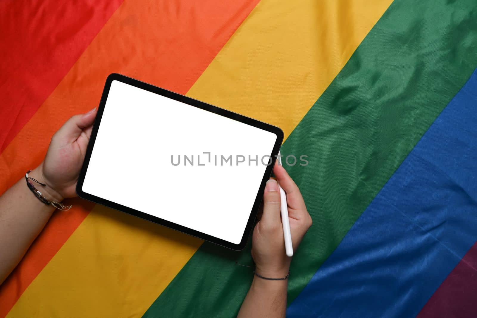 Man holding digital tablet over colorful rainbow flag. LGBT.