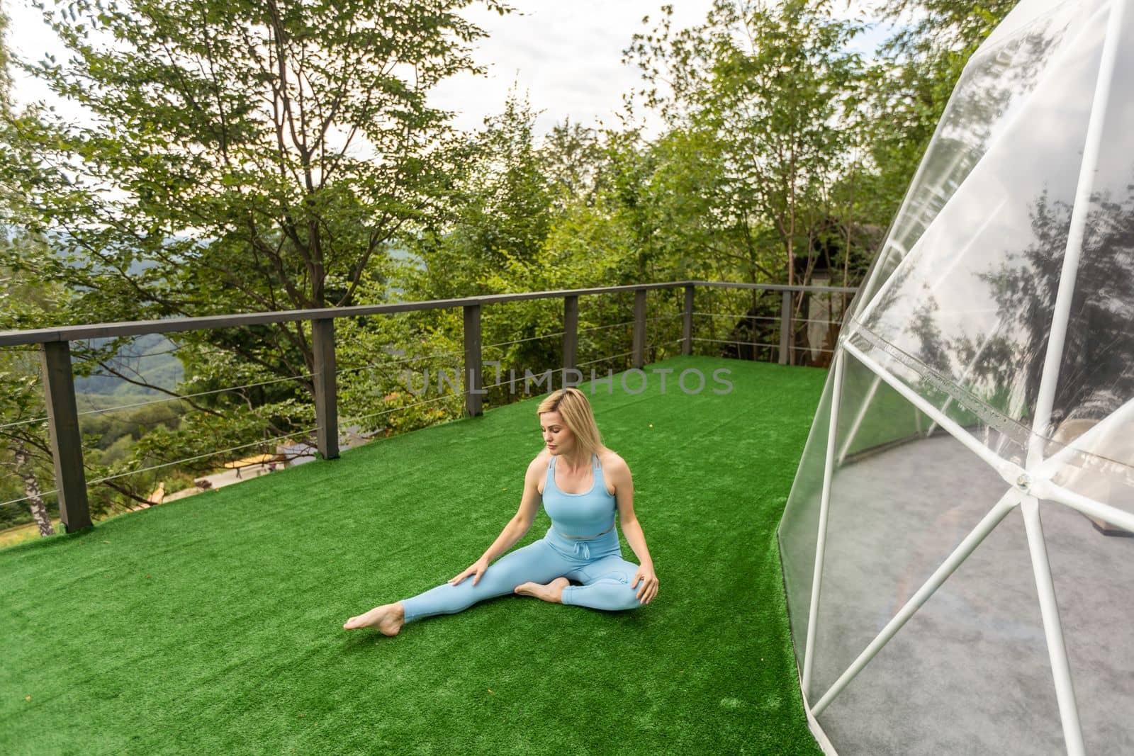 a woman is doing exercises on the terrace of a transparent bubble dome.
