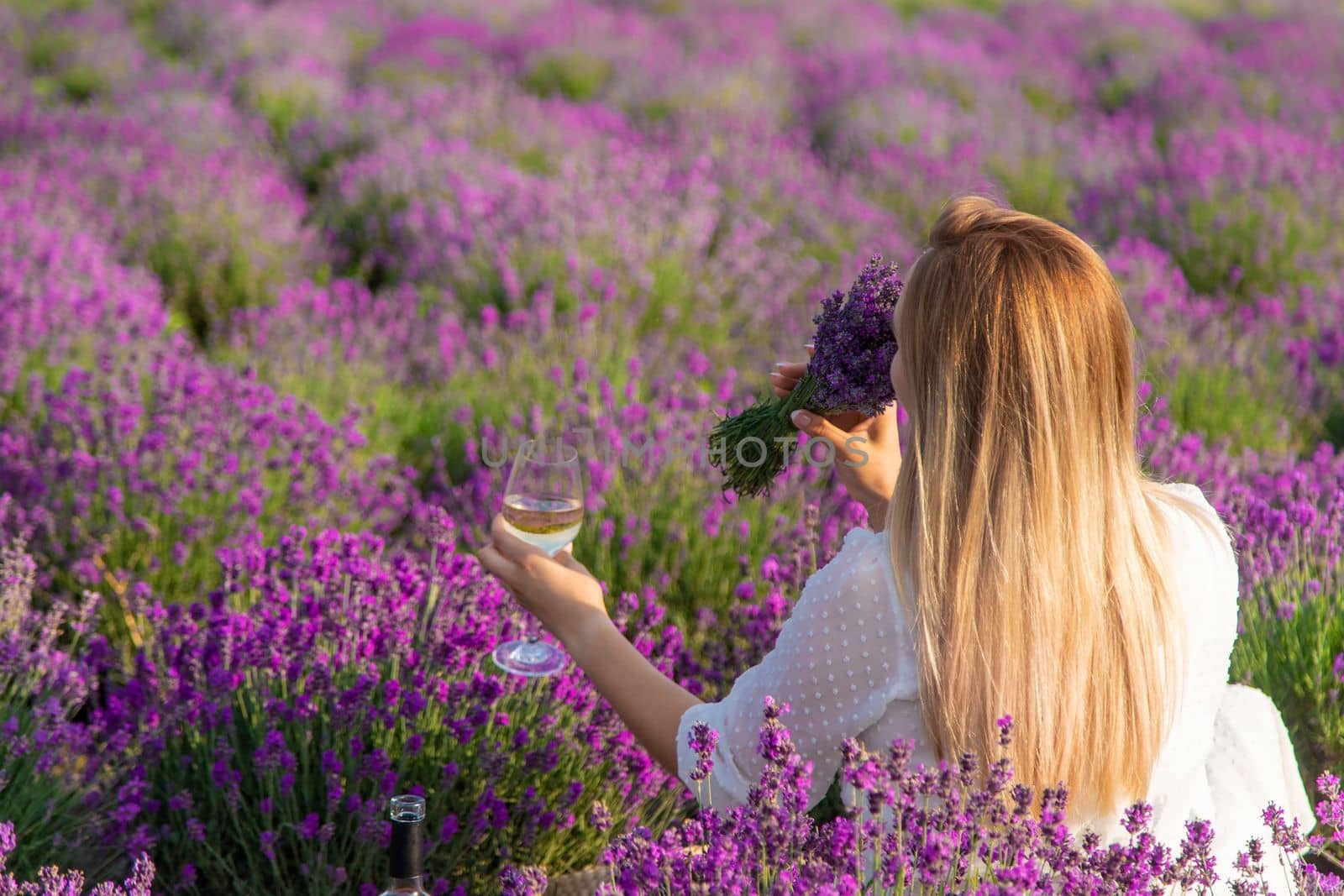 the girl holds a glass of wine on the background of a lavender field. Selective focus. Nature