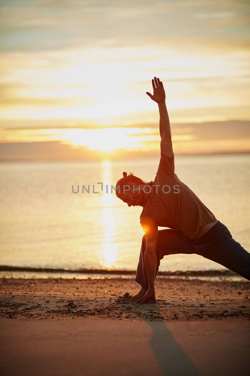 Nature is the perfect yoga partner. a man practicing the triangle pose during his yoga routine at the beach