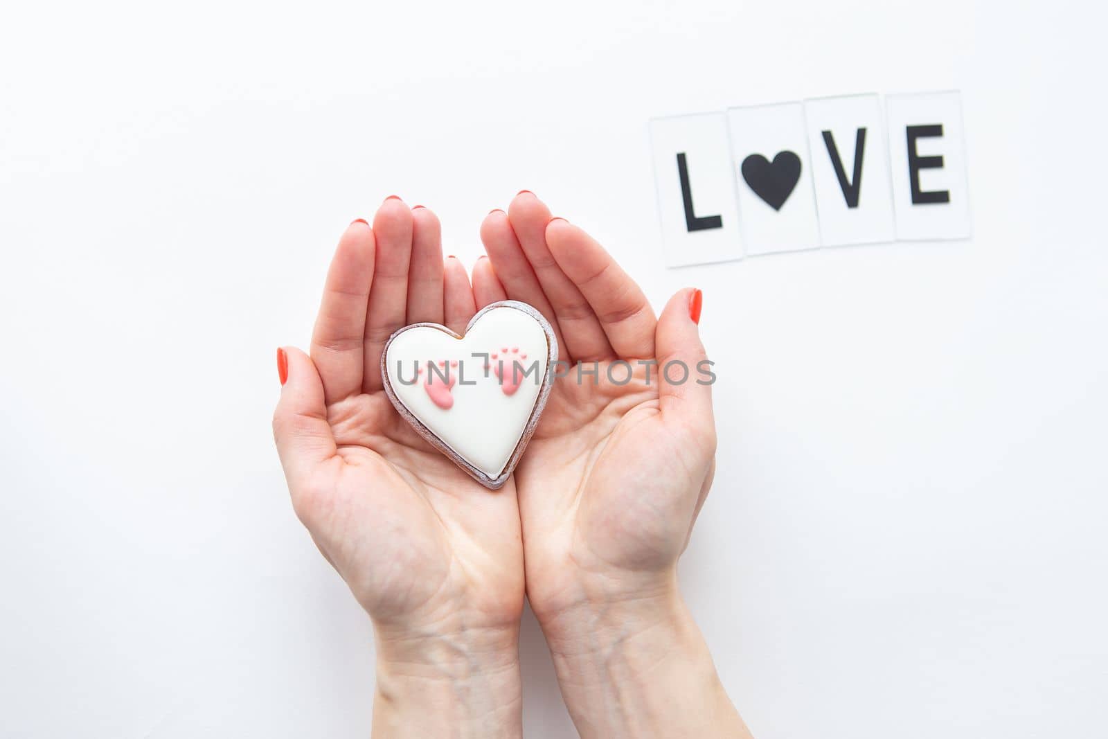 Beautiful children's footprint in the shape of a heart, the girl's hands hug the heart. Love lettering. by sfinks