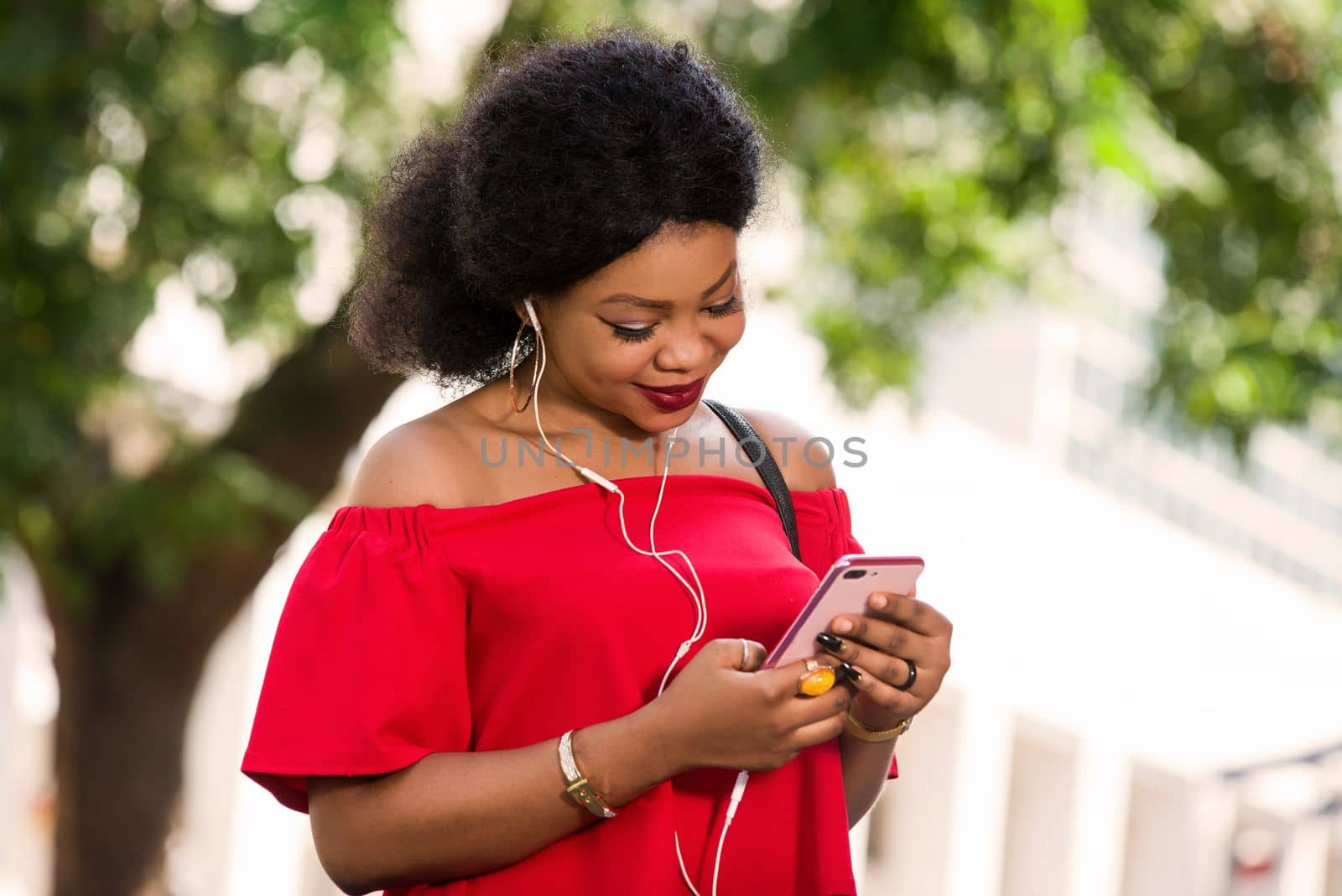 Happy young woman wearing a red t-shirt with headphones talking on the mobile phone in the city