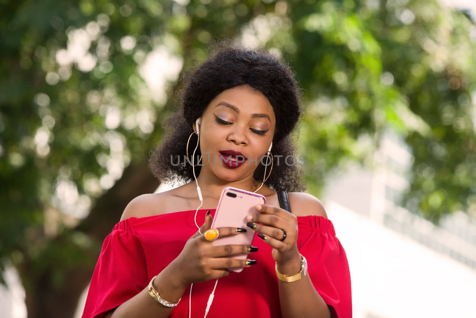 Happy young woman wearing a red t-shirt with headphones talking on the mobile phone in the city