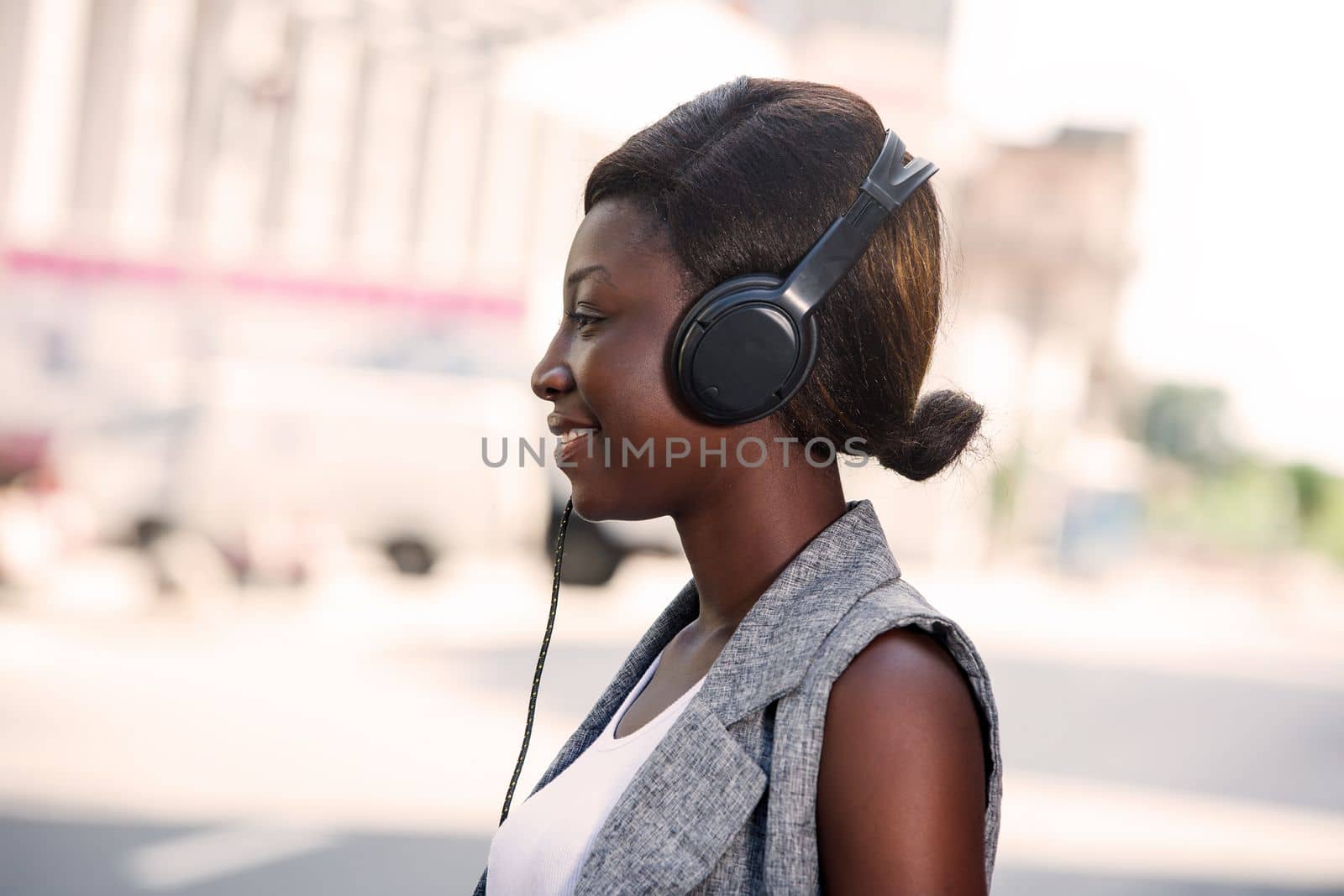 Attractive and beautiful young woman standing on an urban street listening to music with headphones