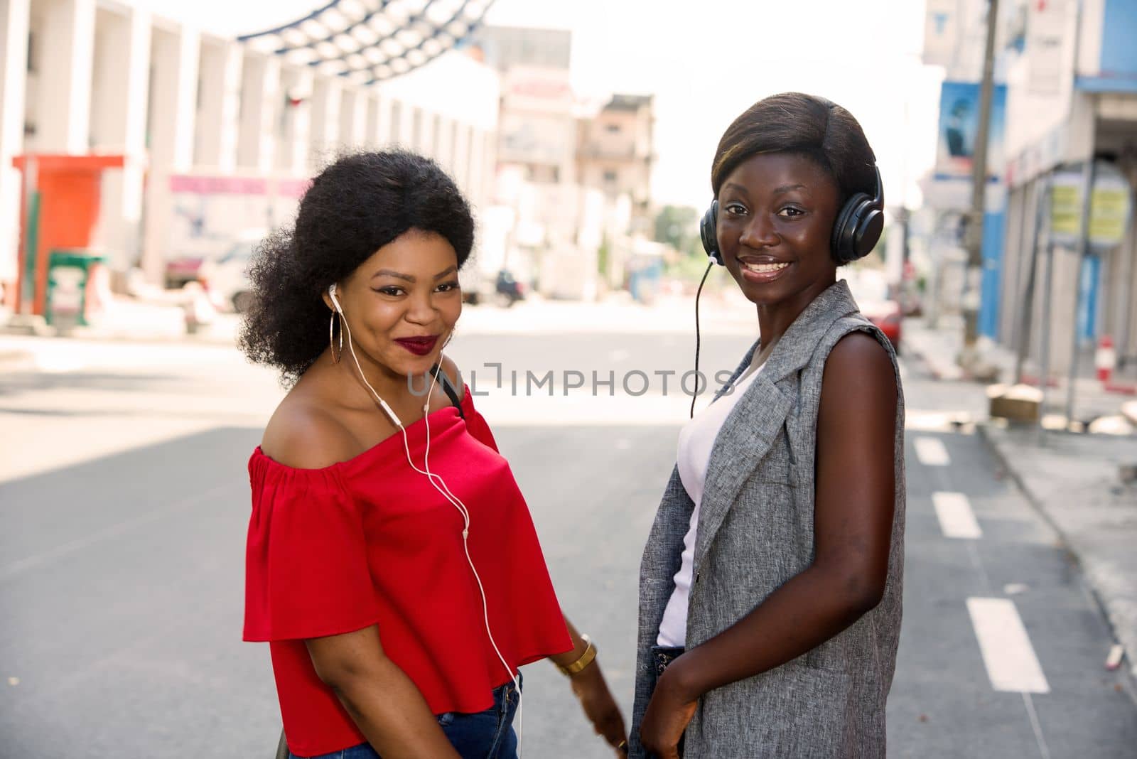 group of two happy smiling friends with headphones listening to music outdoors.persons, friendship and international concept