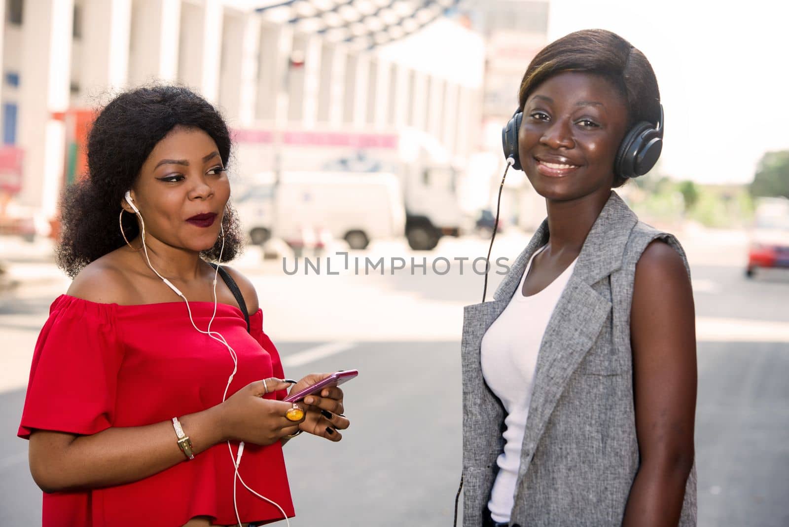 group of two happy smiling friends with headphones listening to music outdoors.persons, friendship and international concept
