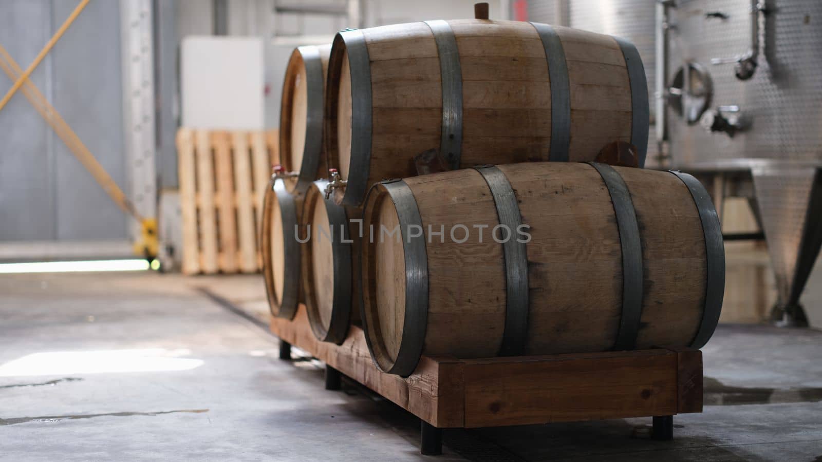 Winery and cognac factory with steel fermentation tanks and wooden barrels for aging process. Food industry and winemaking concept