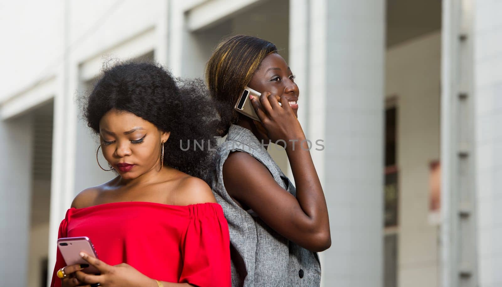 two young smiling women standing back outside and talking on the phone.concept communication and youth