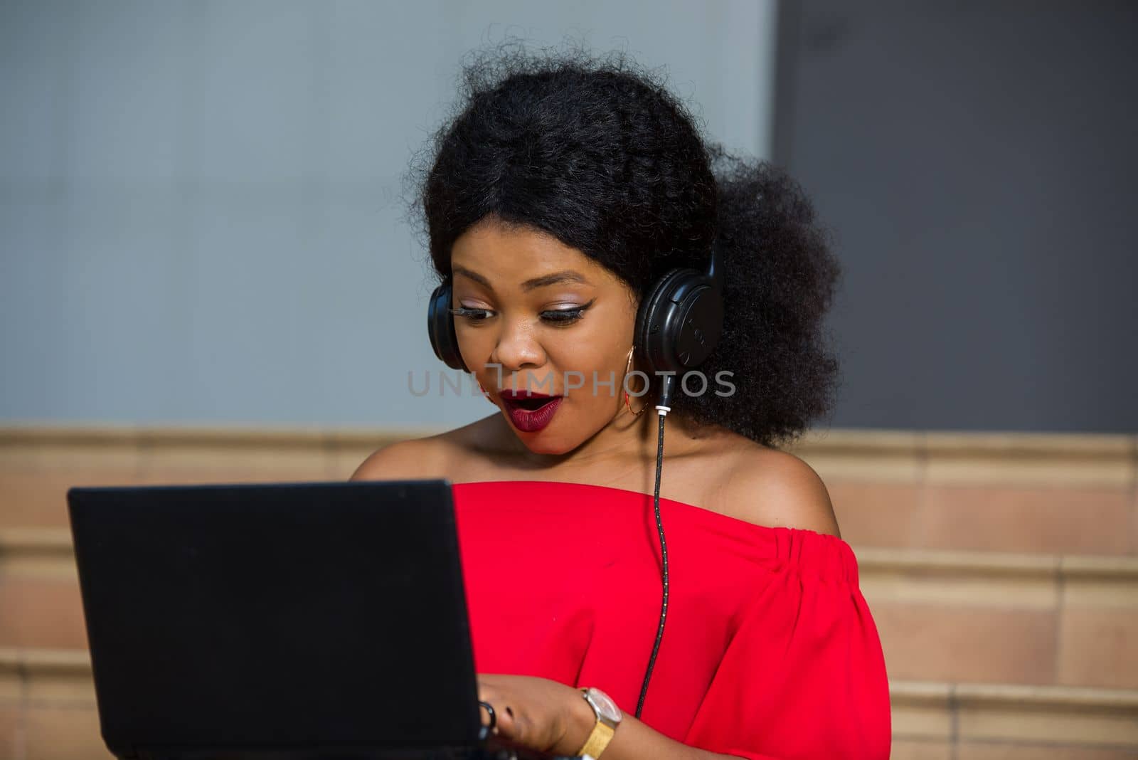 young girl sitting with laptop listening to music using headphones.
