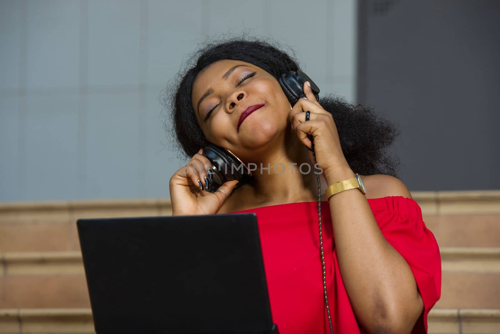young girl sitting with laptop listening to music using headphones.
