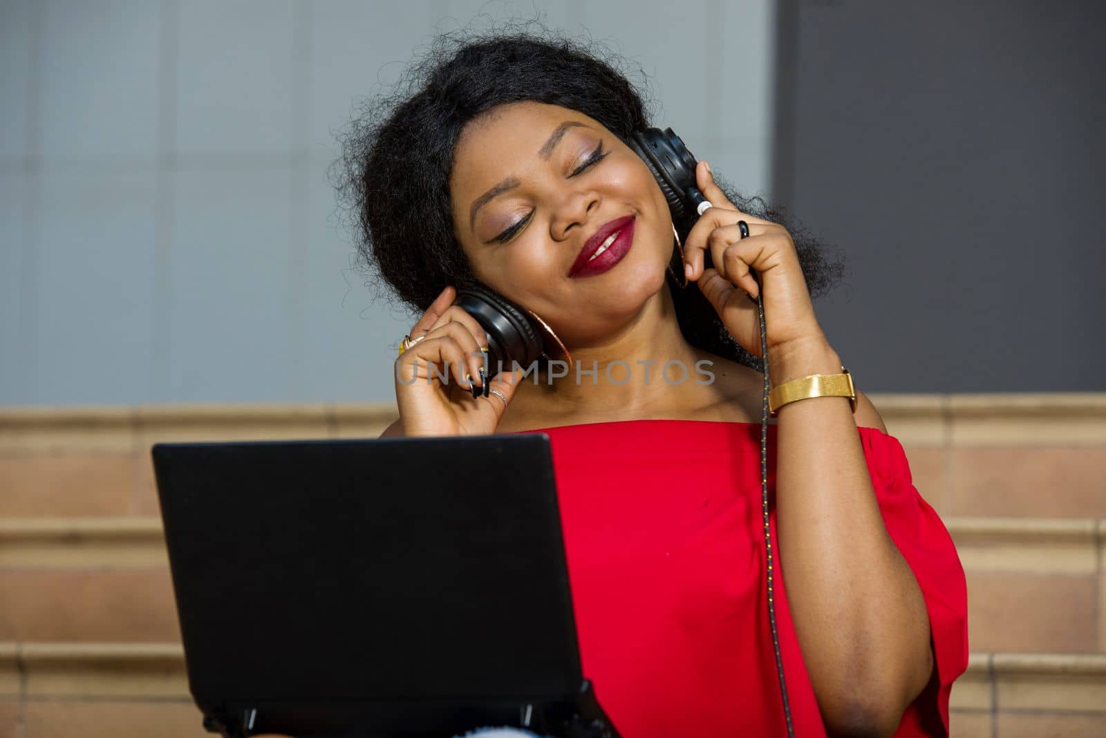 young girl sitting with laptop listening to music using headphones while smiling