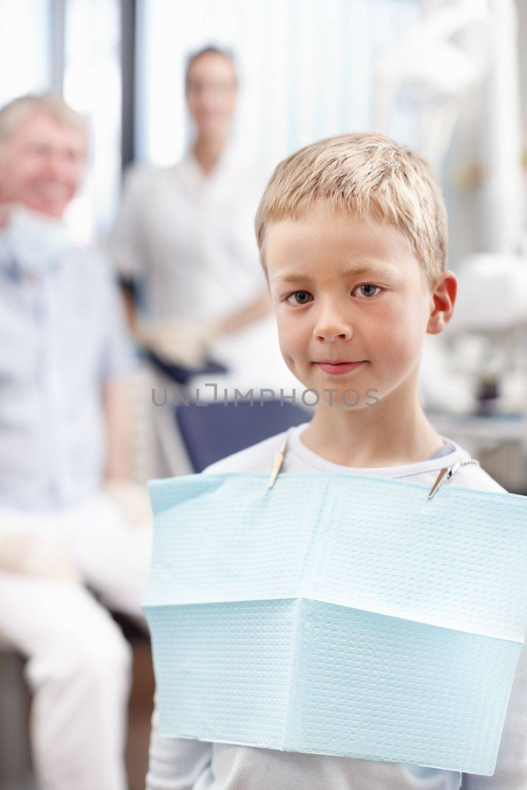 Smiling boy at dentists office. Portrait of cute young boy smiling with doctors in background