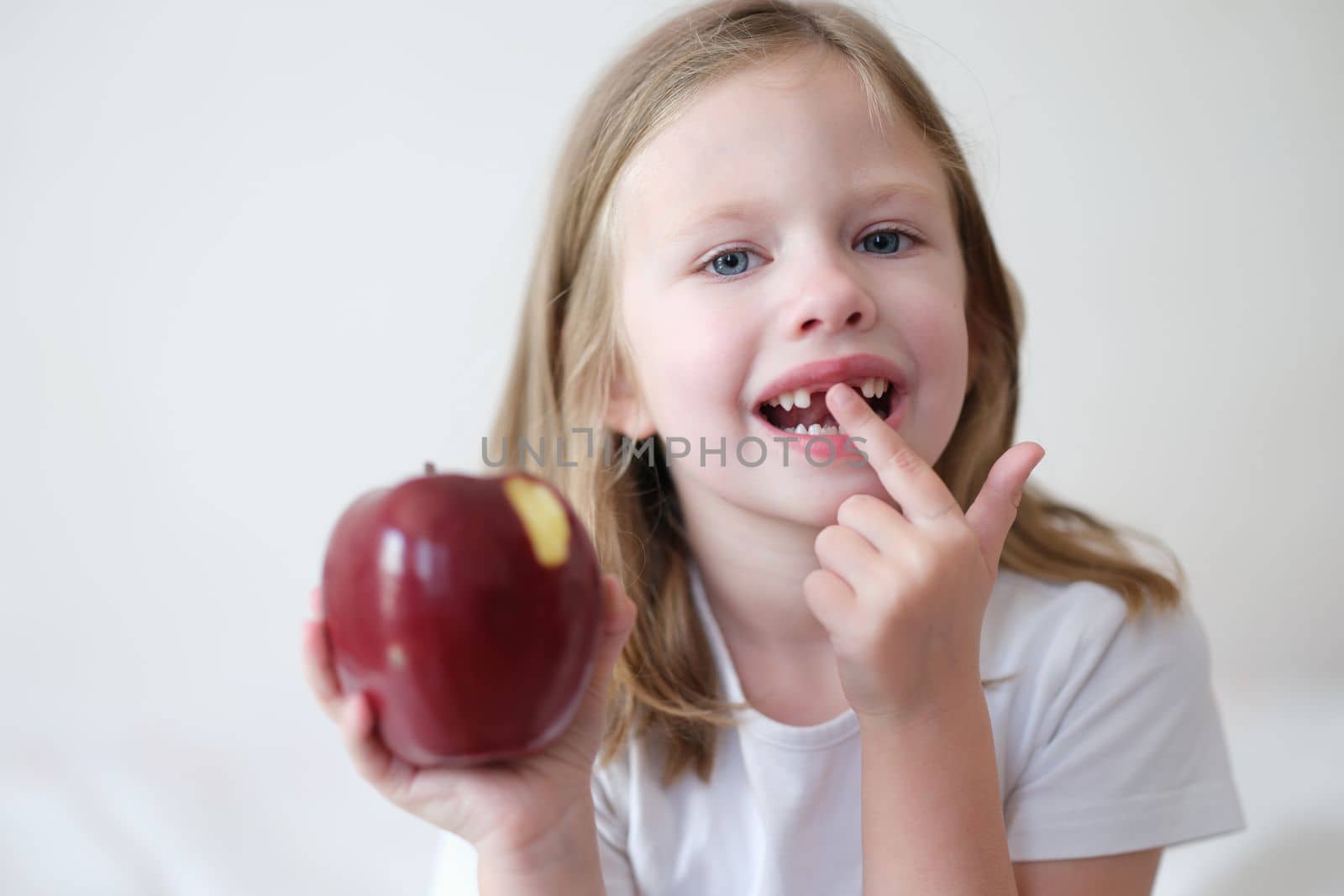 Portrait of a beautiful little girl without teeth with apple. Products useful for teeth concept