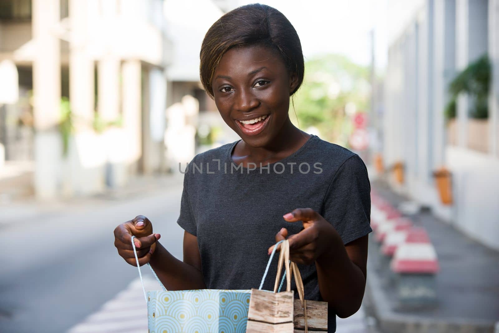 young happy woman standing in an urban environment and carrying shopping bags.
