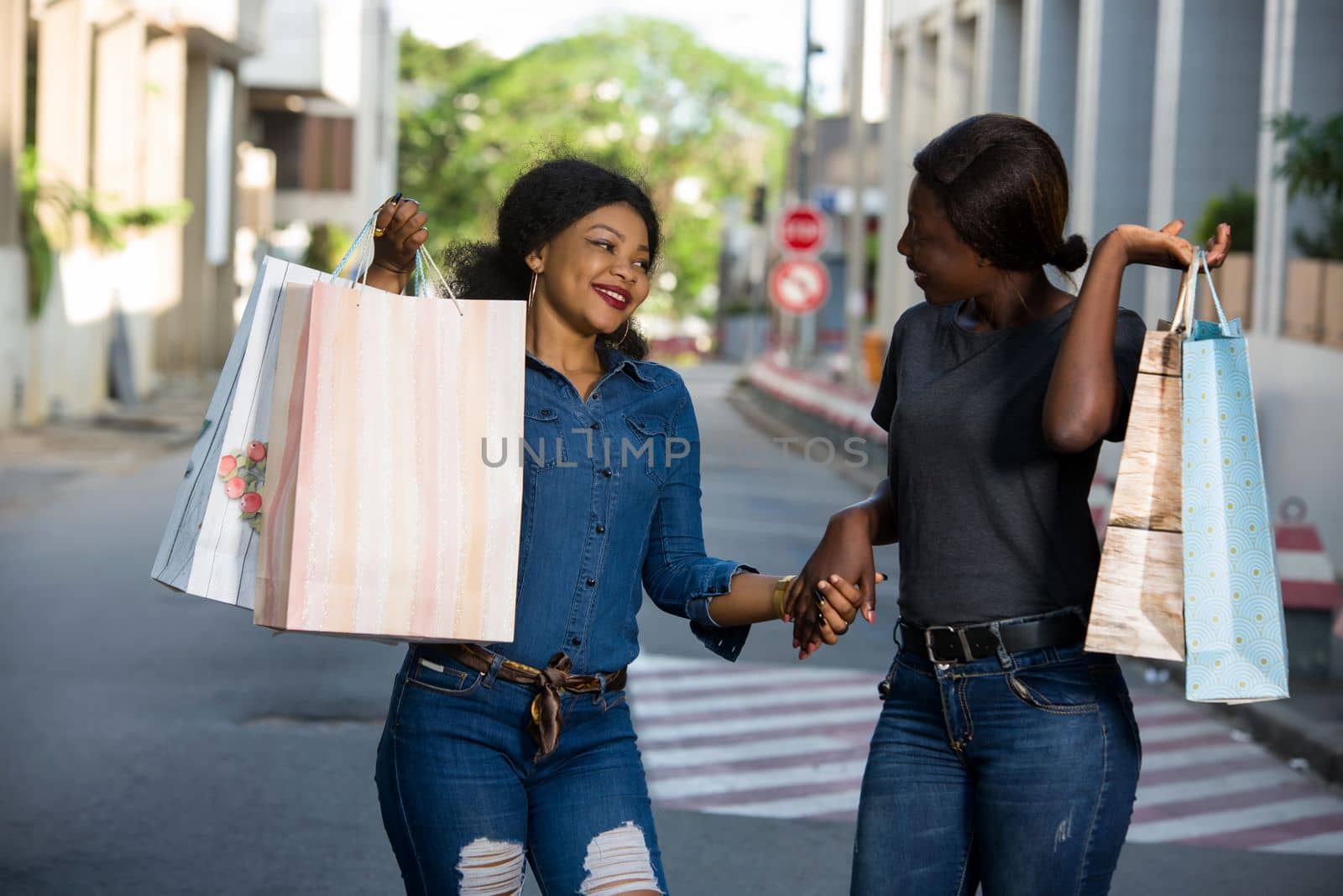 two happy young women with shopping bag walking and jumping for joy in the city