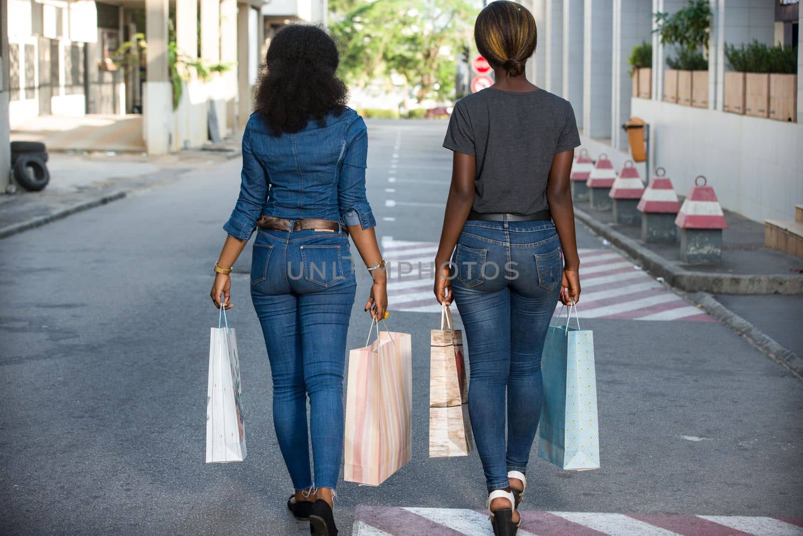 two cheerful girls walking down the street after shopping at the mall