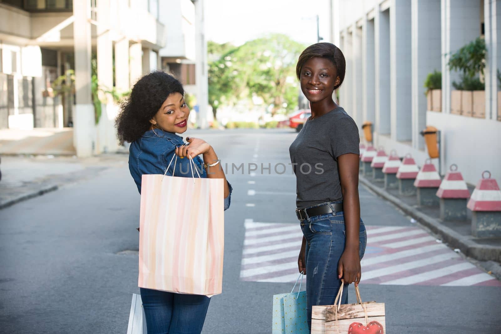 two cheerful girls walking down the street after shopping at the mall